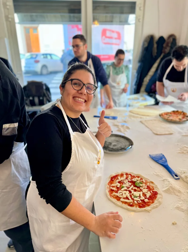 Una corsista mostra la sua pizza napoletana appena sfornata